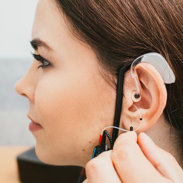 Audiologist programming hearing aid acoustic response using the software. Young woman getting hearing aid adjustments